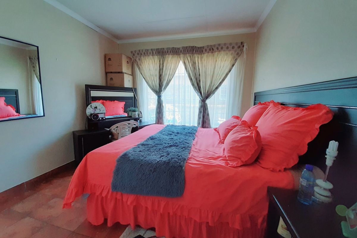 A bedroom featuring tiled flooring, a window with curtain tracks, and a built-in mirror.