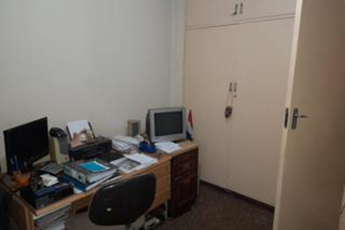 A compact bedroom featuring built-in cupboards and neutral wall finishes, suitable for use as a home office or guest room.