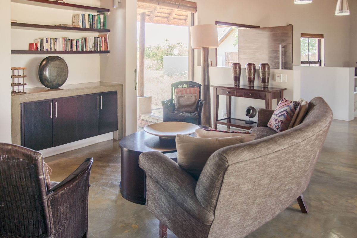 A comfortable living room featuring polished concrete flooring, built-in cabinetry with shelving, and direct access to an outdoor patio area.