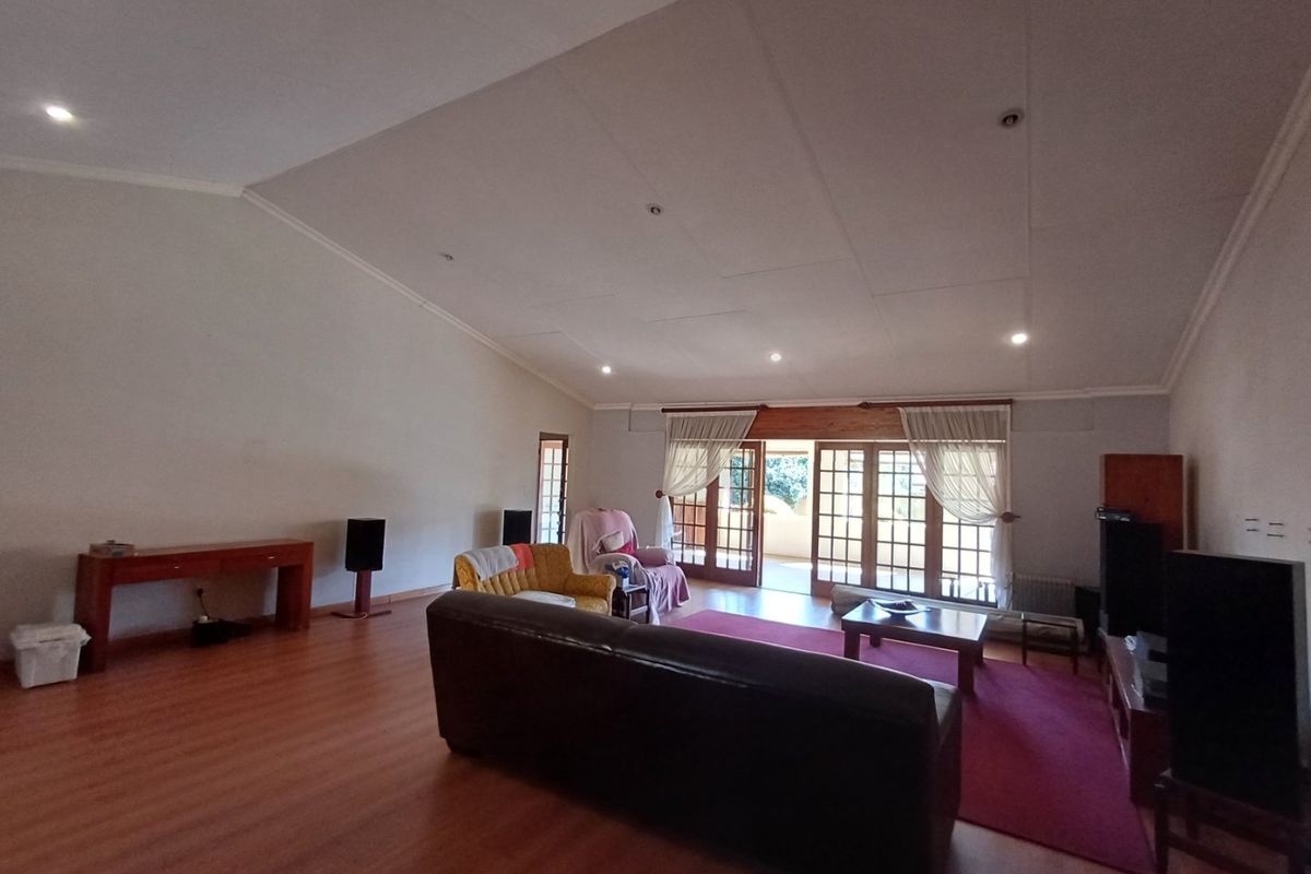 Spacious living room featuring vaulted ceilings, recessed lighting, and large wooden framed glass doors providing access to the outdoor area.