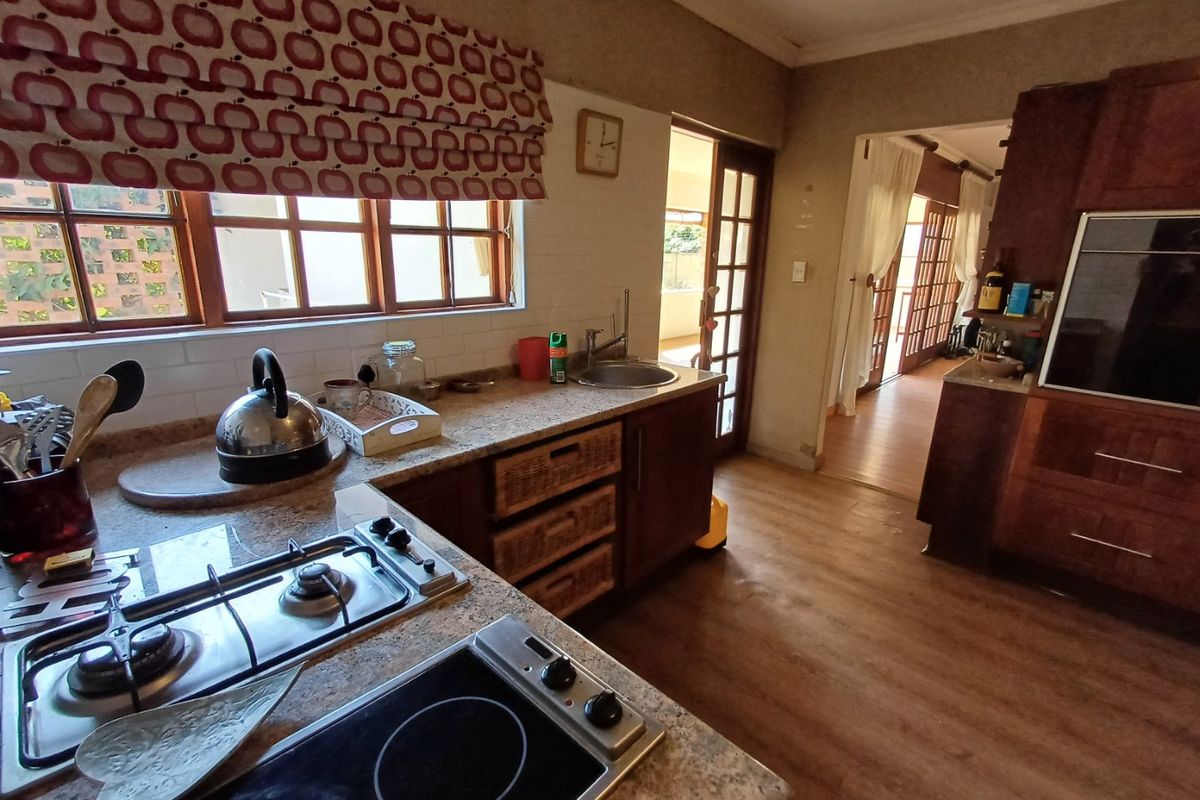 A functional kitchen featuring granite countertops, a built-in gas hob, electric cooktop, and integrated oven, with direct access to the adjacent living area.