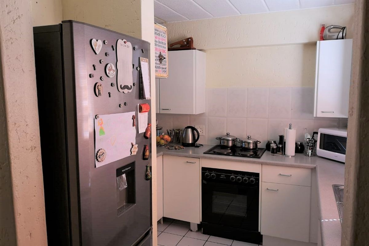 Compact kitchen featuring white cabinetry, tiled backsplash, built-in oven with hob, and tiled flooring.