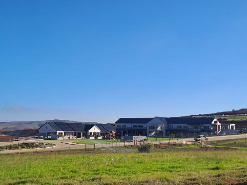 A wide-angle view of a modern property complex featuring multiple buildings, solar panel installations, and expansive landscaped grounds.