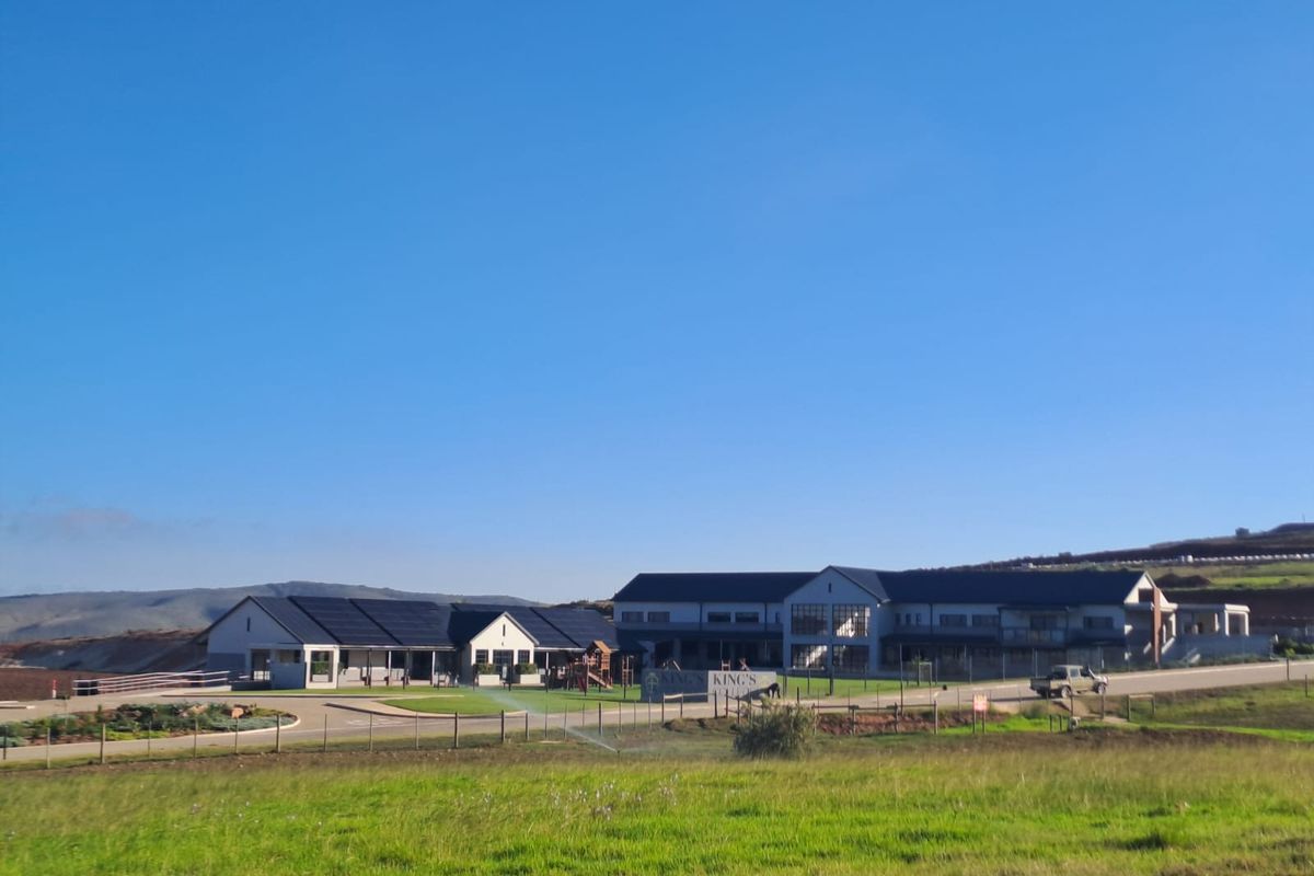 A wide-angle view of a modern property complex featuring multiple buildings, solar panel installations, and expansive landscaped grounds.