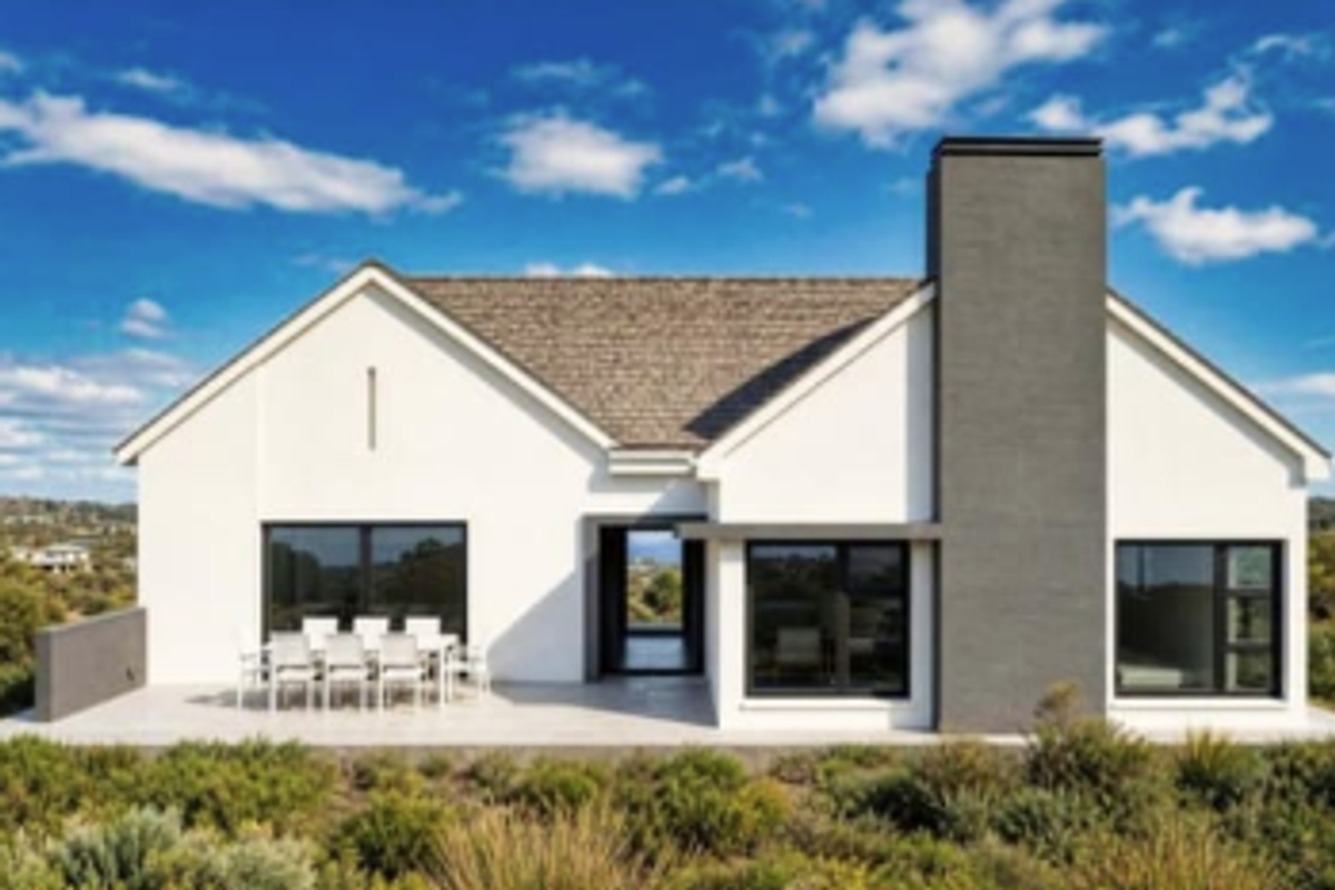 Rear elevation of a modern house featuring a paved patio, large sliding glass doors, and a prominent chimney, set against a landscaped garden.