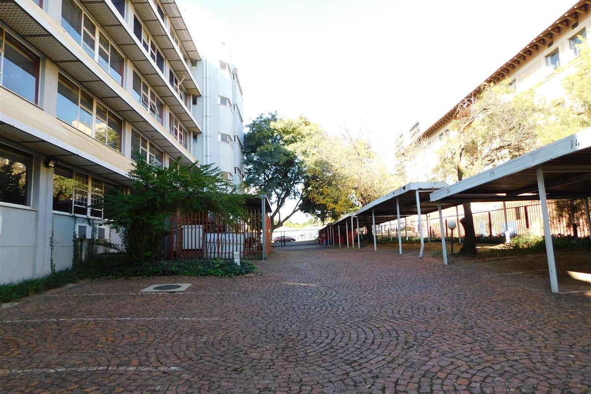 Exterior view of the office complex featuring paved parking area and covered carport bays between the multi-story office buildings.