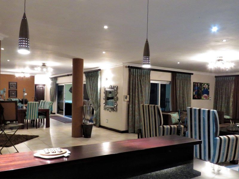 Spacious open-plan living and dining area featuring tiled flooring, recessed lighting, and a central structural column, creating a versatile and connected living space.