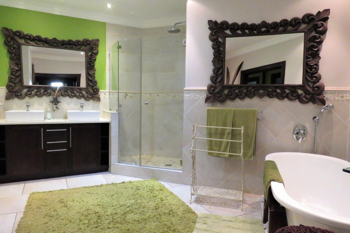 Spacious bathroom featuring a double vanity, glass-enclosed shower, and a freestanding bathtub with neutral wall tiling and modern fixtures.