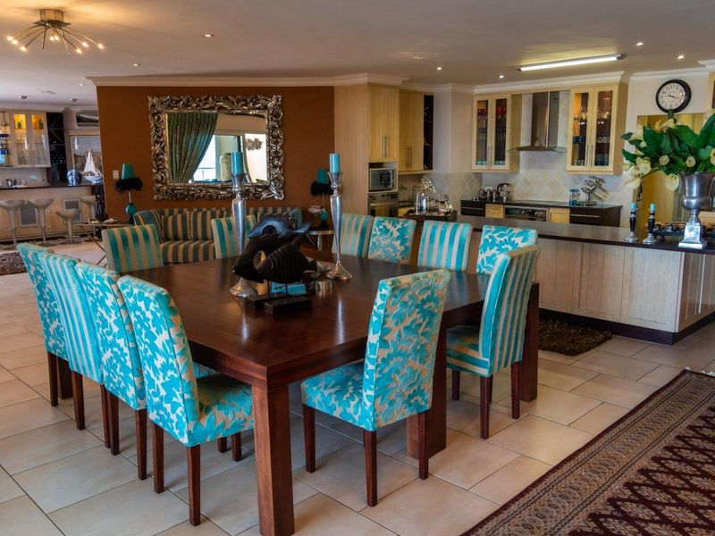 Spacious open-plan living and dining area featuring a modern kitchen with island, breakfast bar, and tiled flooring throughout.