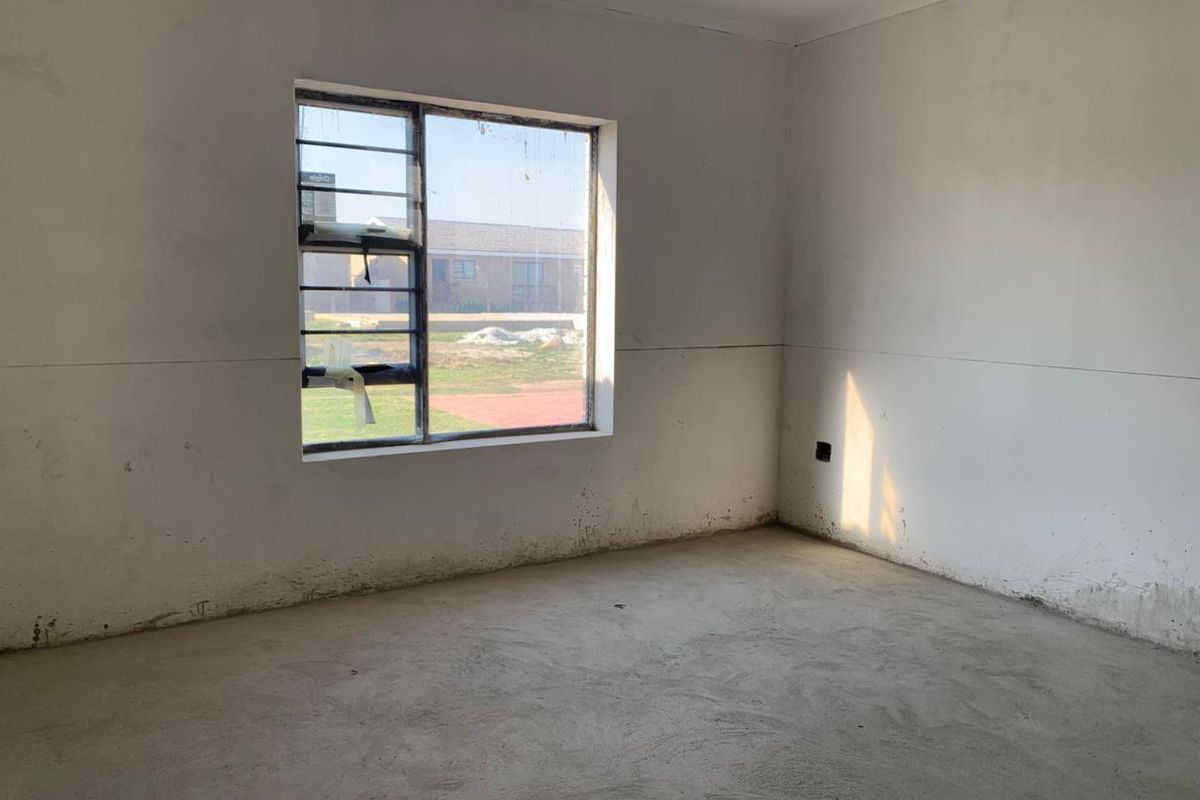 An empty, unfinished bedroom featuring bare concrete flooring and plain walls, awaiting final finishes and flooring installation.