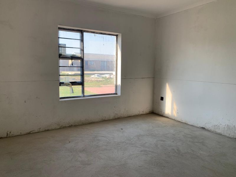An empty, unfinished bedroom featuring bare concrete flooring and plain walls, awaiting final finishes and flooring installation.