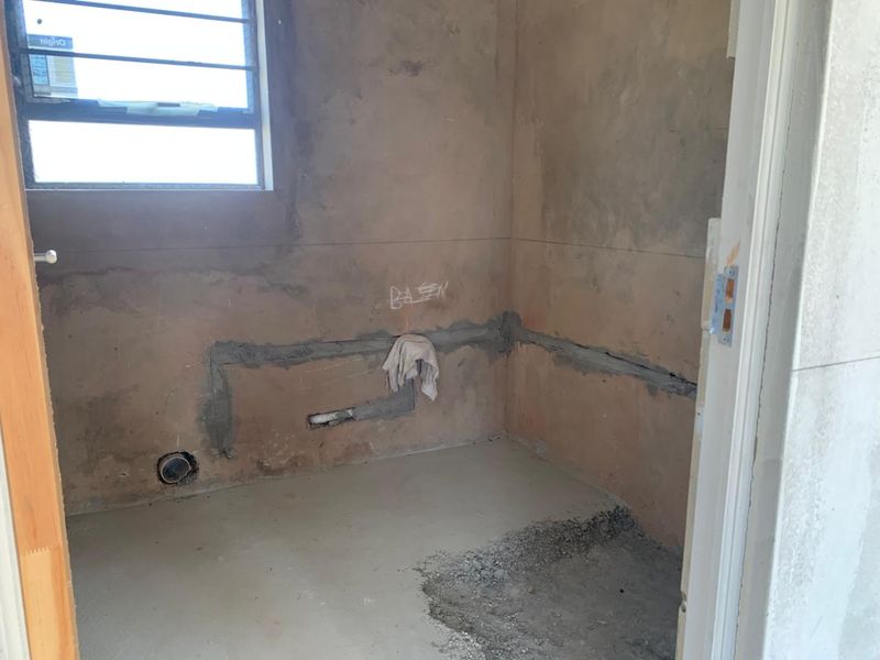 An unfinished bathroom space in shell condition, featuring exposed plumbing rough-ins and bare wall surfaces, ready for final tiling and fixture installation.