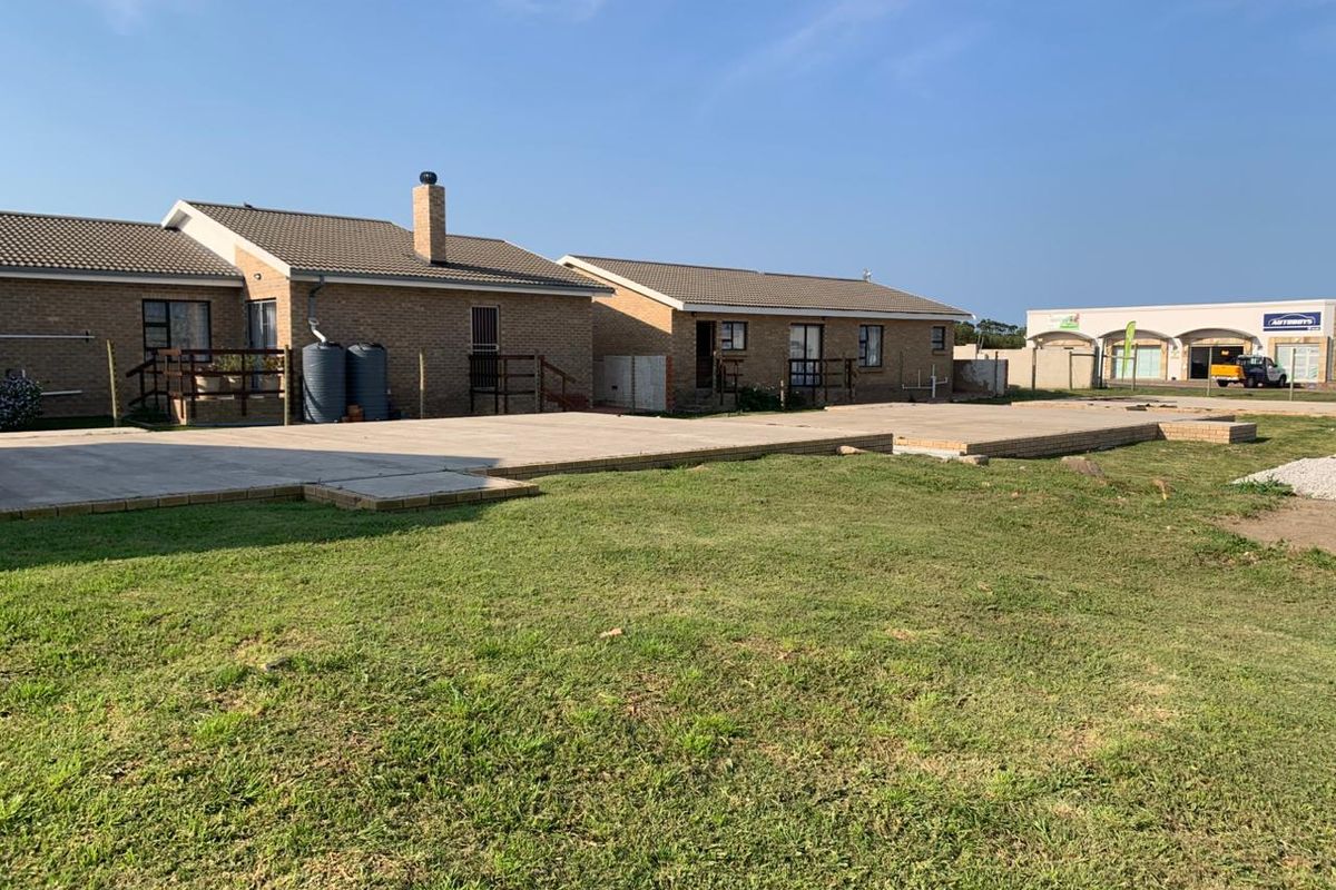 Rear view of the retirement village units featuring a large concrete patio area, brick construction, and installed water tanks.