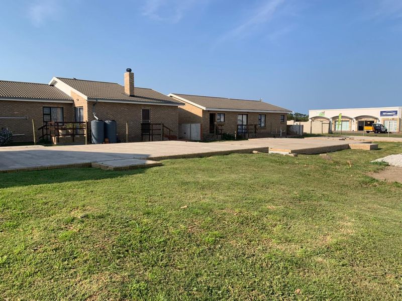 Rear view of the retirement village units featuring a large concrete patio area, brick construction, and installed water tanks.