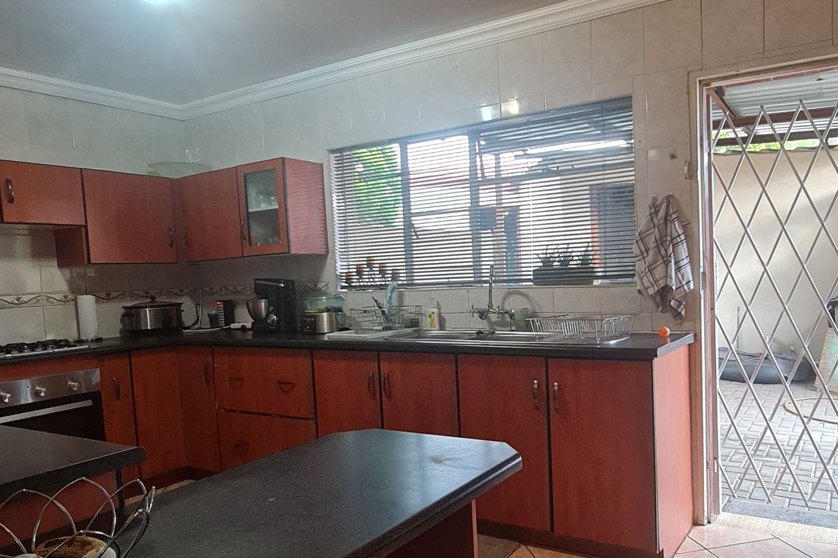 Functional kitchen featuring wooden cabinetry, dark countertops, tiled flooring, and direct access to an outdoor area through a security gate.
