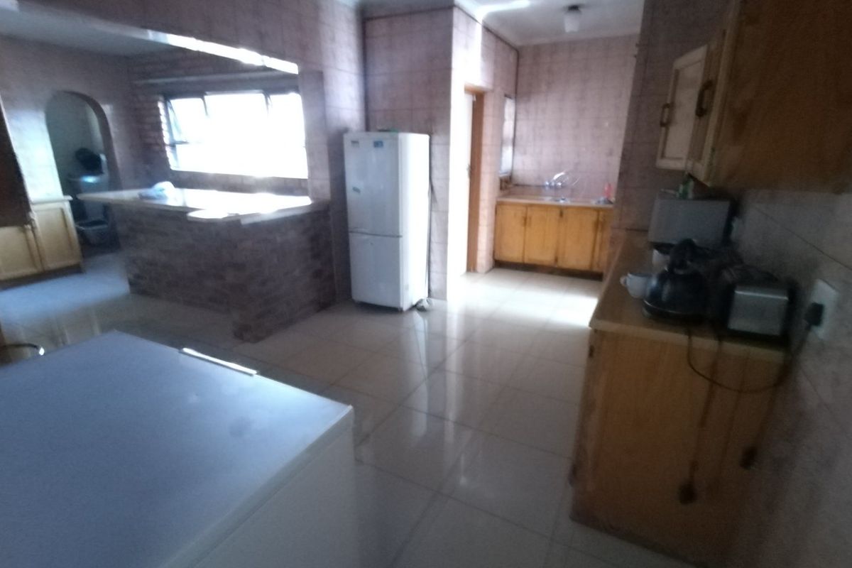 A dated kitchen featuring tiled walls, wooden cabinetry, and a breakfast bar, offering a functional layout with potential for modernization.