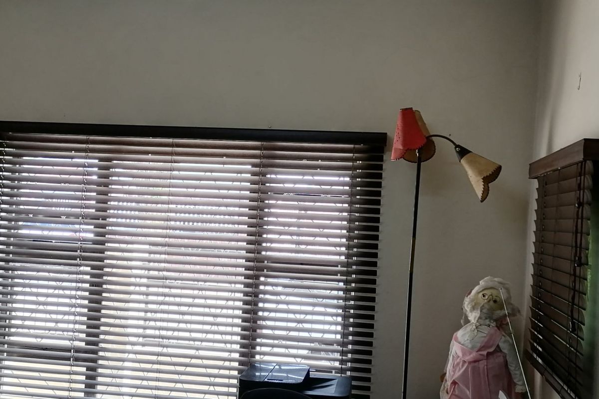 A bedroom interior featuring dark venetian blinds on the windows and plain wall finishes.