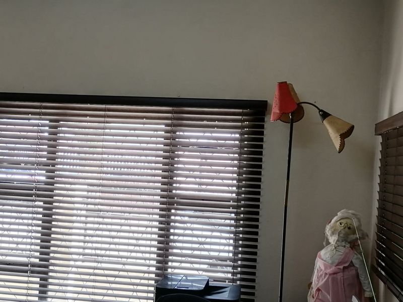 A bedroom interior featuring dark venetian blinds on the windows and plain wall finishes.
