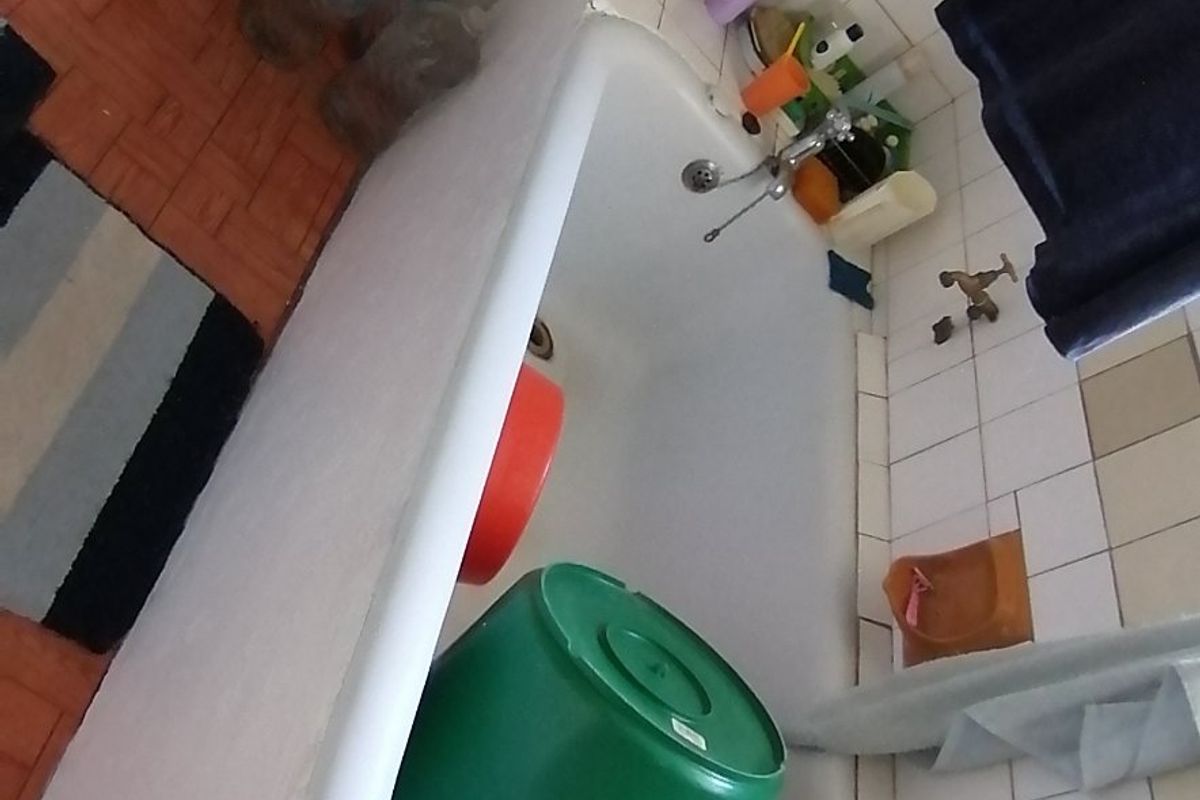 A dated bathroom featuring a standard bathtub and toilet with wall tiling, requiring cosmetic updates to improve its overall condition and appeal.