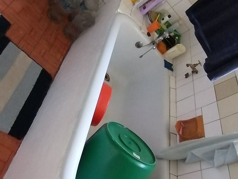 A dated bathroom featuring a standard bathtub and toilet with wall tiling, requiring cosmetic updates to improve its overall condition and appeal.