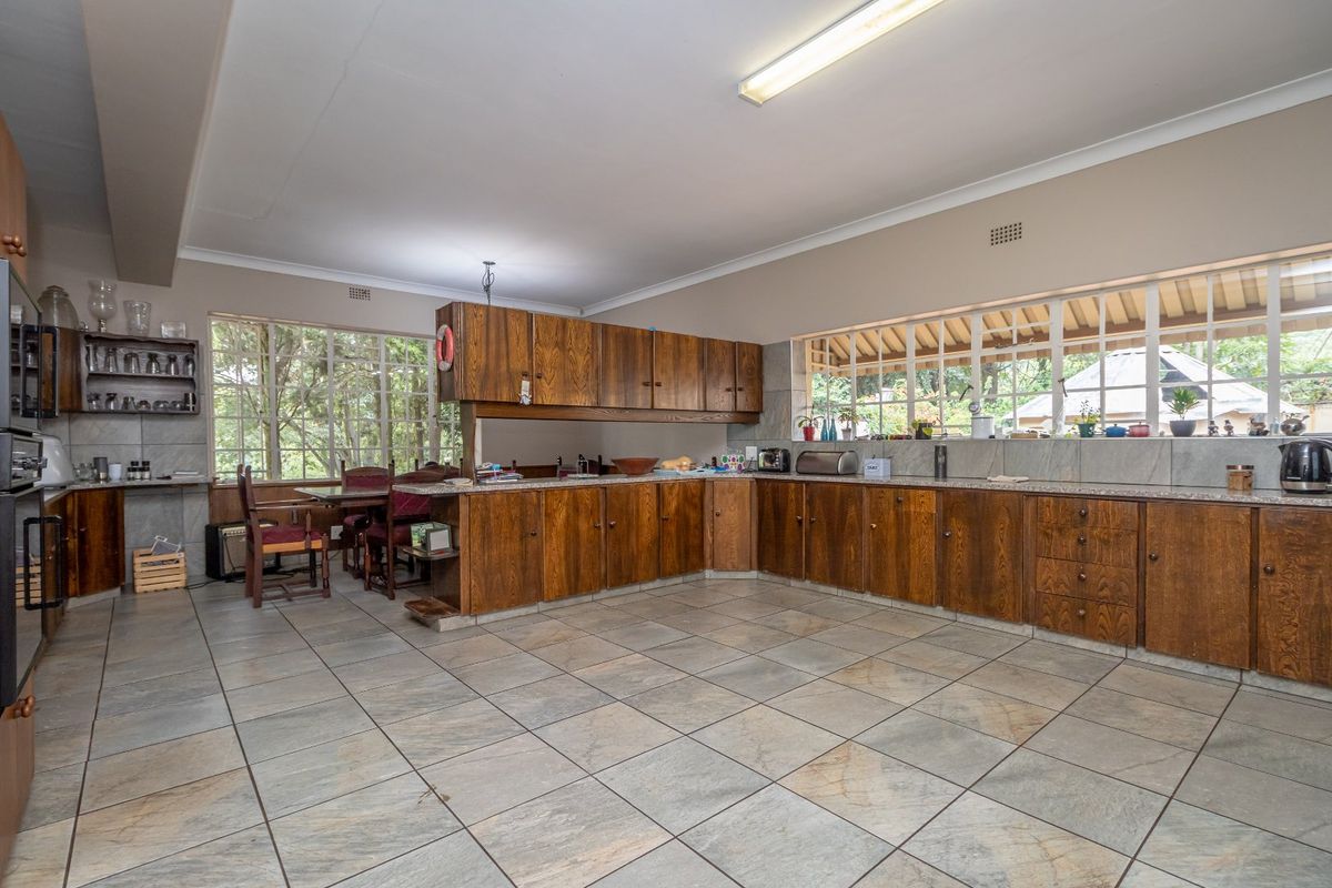 Spacious kitchen featuring extensive wooden cabinetry, stone-look countertops, tiled flooring, and large windows providing ample natural light.