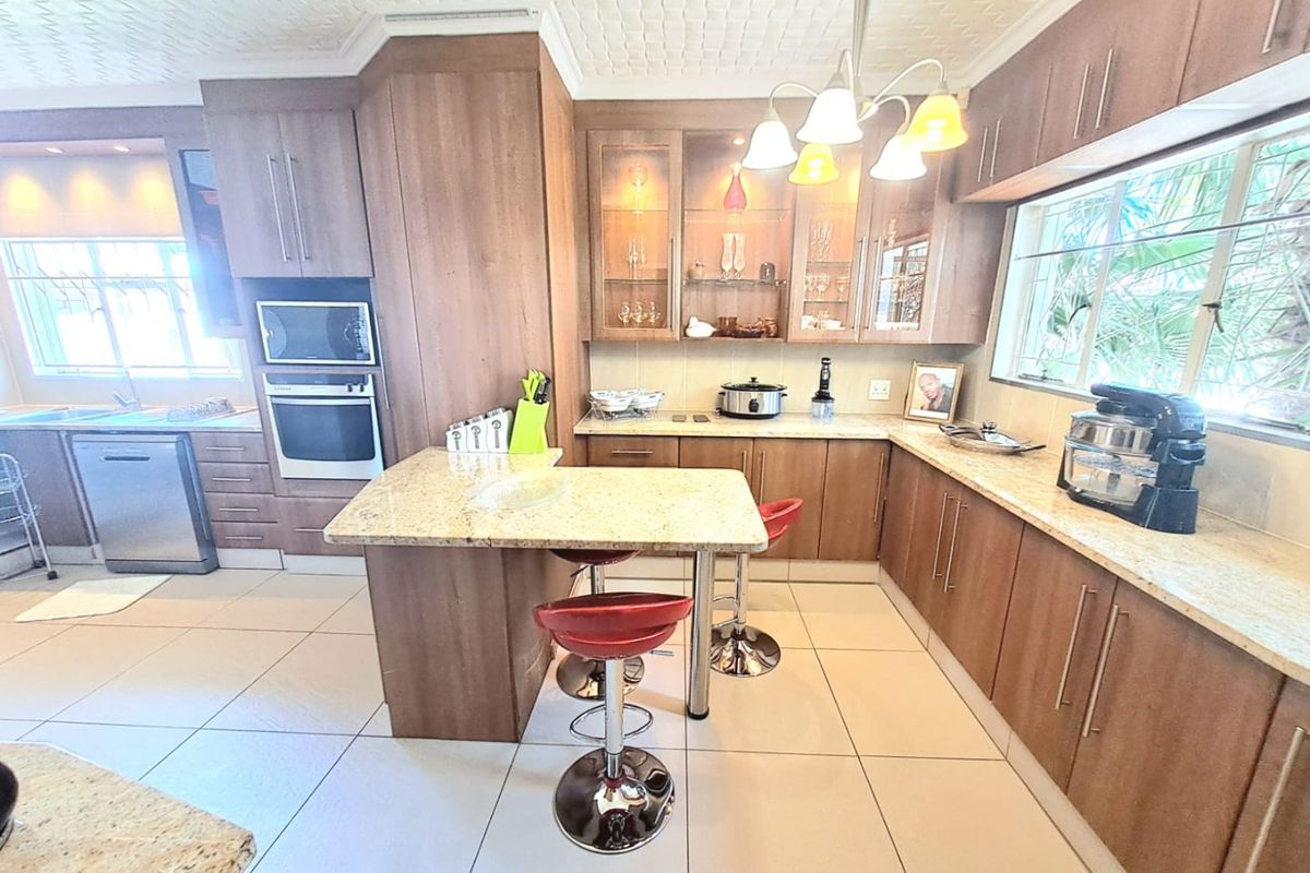 A functional kitchen featuring wood-finish cabinetry, granite countertops, a built-in oven, microwave, and a breakfast nook island.