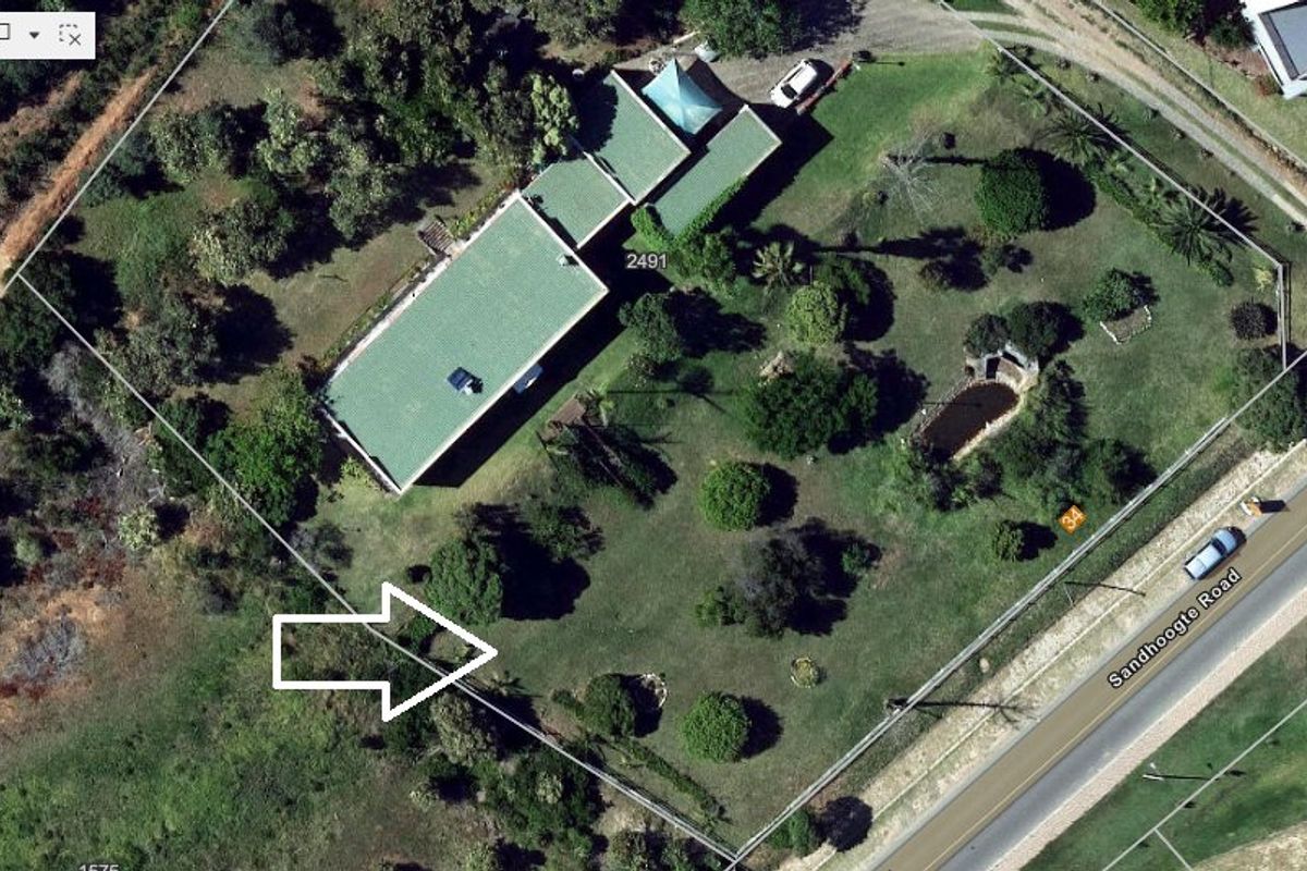 Aerial view of a residential property featuring a green roof dwelling, a garden pond, and established landscaping on a large plot.