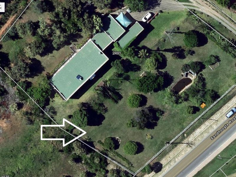 Aerial view of a residential property featuring a green roof dwelling, a garden pond, and established landscaping on a large plot.