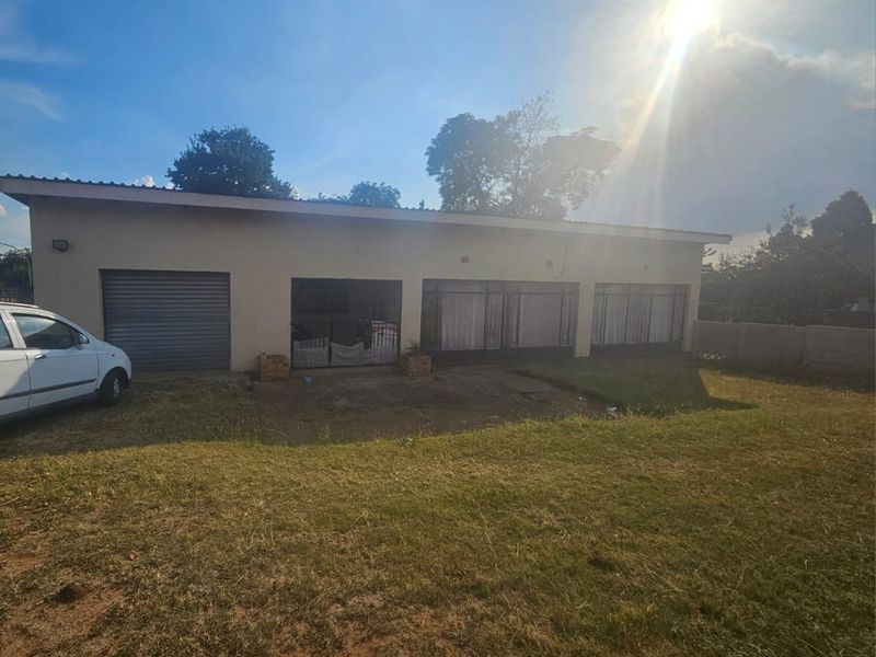 Rear view of the property featuring a single garage, security gates, and a large backyard area.