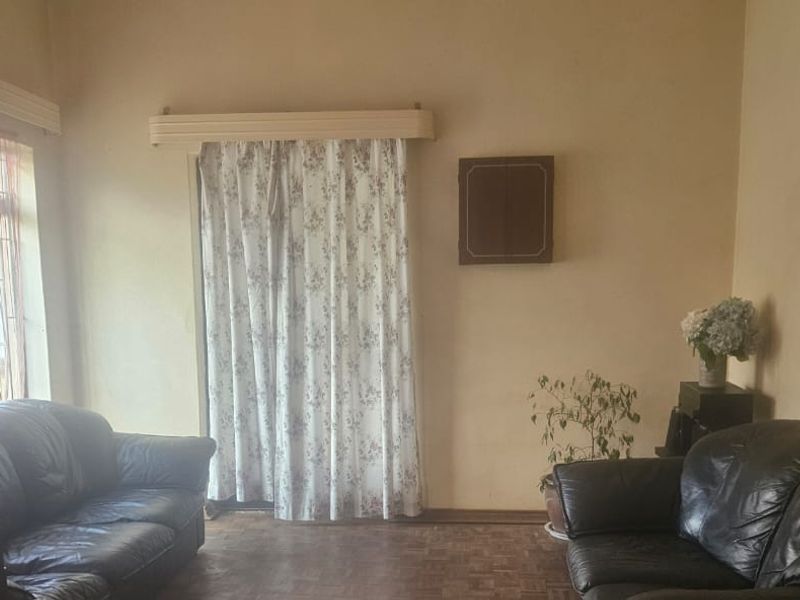 A living room featuring parquet flooring and curtain rails, requiring cosmetic updates to the wall finishes to improve the overall aesthetic.