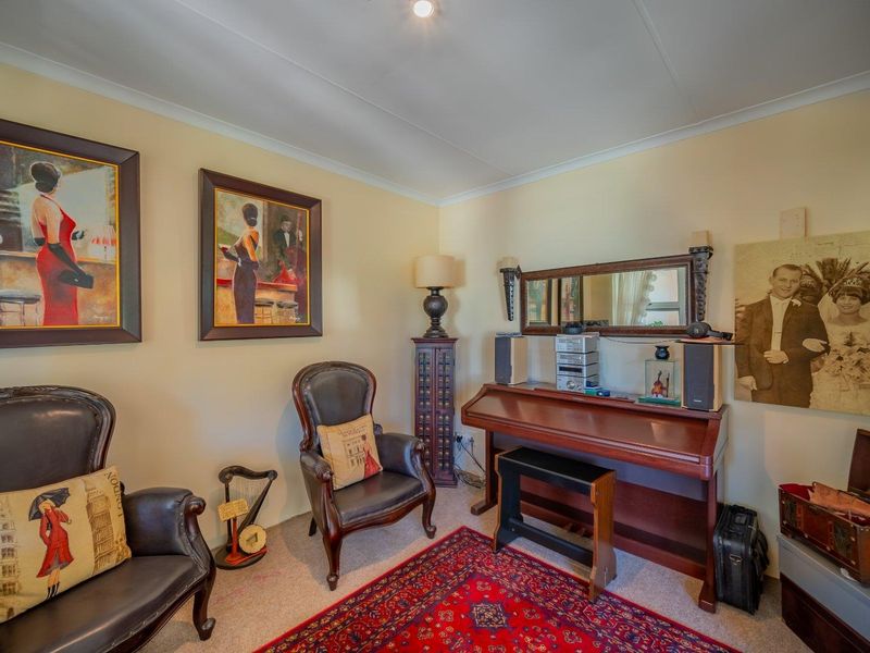 A cozy living area featuring neutral wall tones, coving, and carpeted flooring, providing a comfortable space for relaxation.