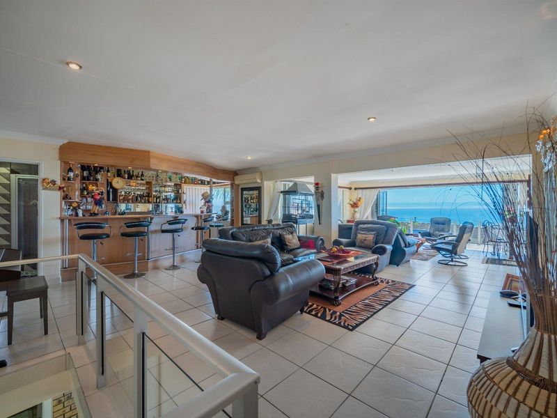 Spacious open-plan living area featuring a built-in bar, tiled flooring, and expansive sliding doors opening to a scenic ocean view.