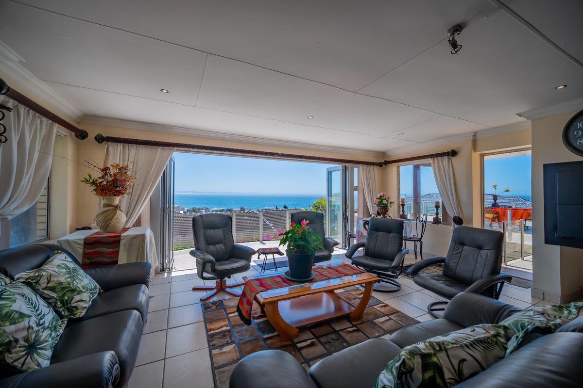 Spacious living room featuring large bi-fold doors that open to a balcony with expansive ocean views, tiled flooring, and recessed lighting.