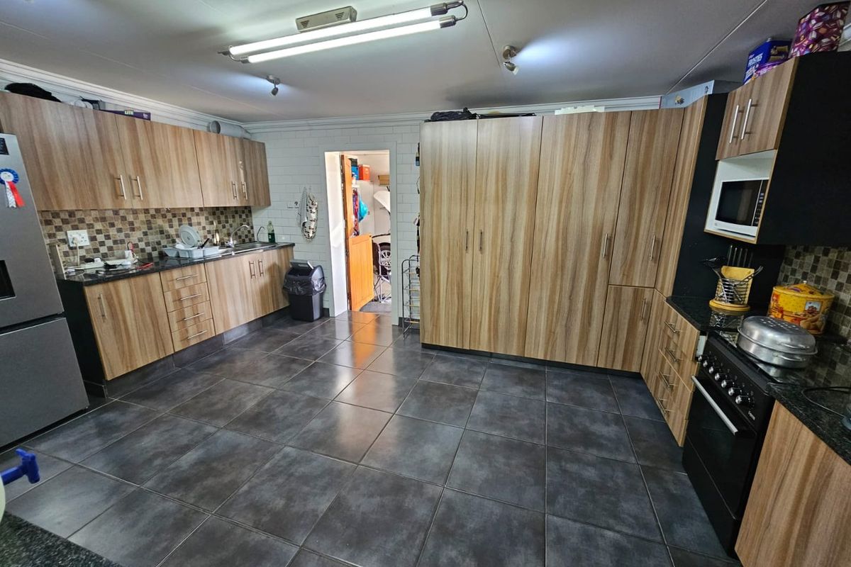 A functional kitchen featuring wood-look cabinetry, dark granite countertops, tiled flooring, and a built-in oven with an integrated microwave.