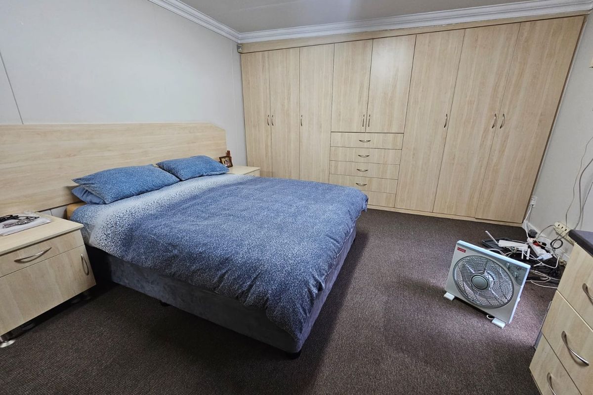 A bedroom featuring extensive built-in light wood cabinetry and matching headboard, providing ample storage space.