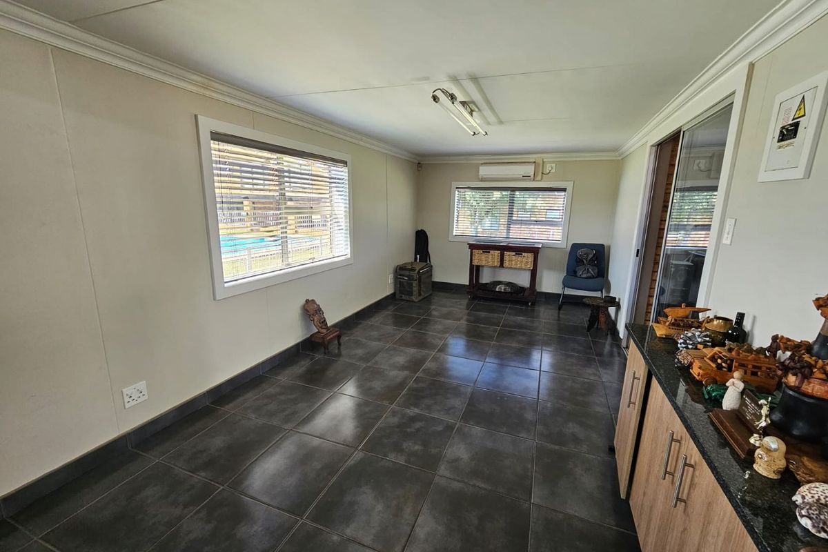 A functional living area featuring dark tiled flooring, a wall-mounted air conditioning unit, and built-in cabinetry with a granite countertop.