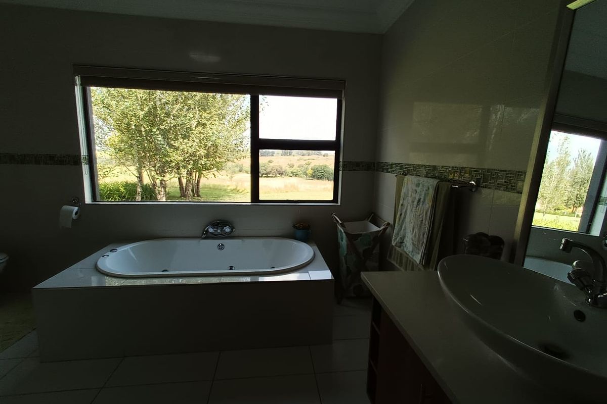 A bright bathroom featuring a built-in bathtub, a vanity with a vessel sink, and large windows offering scenic views of the surrounding landscape.