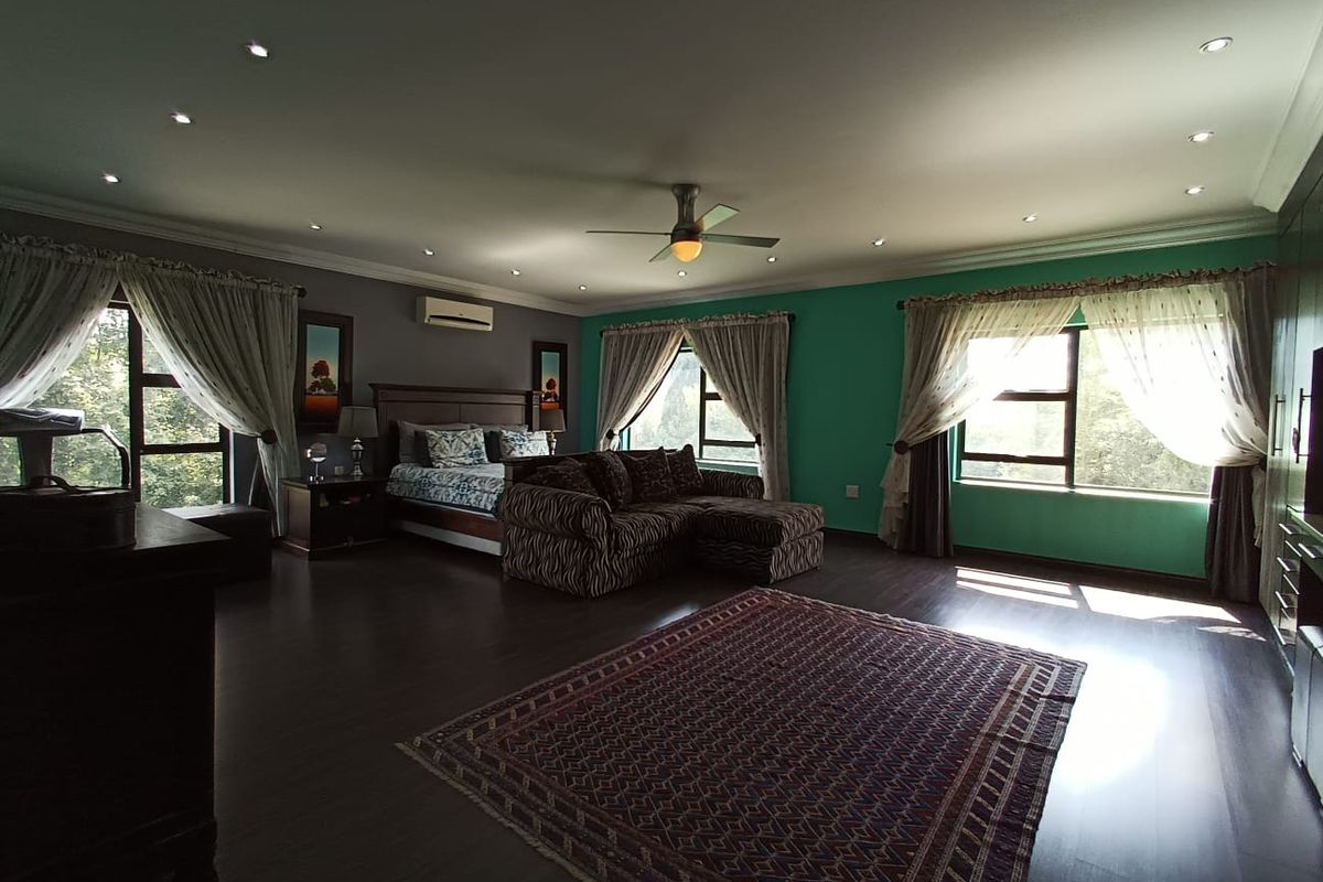 Spacious bedroom featuring dark wood-look flooring, recessed ceiling lighting, a ceiling fan, and an integrated wall-mounted air conditioning unit.