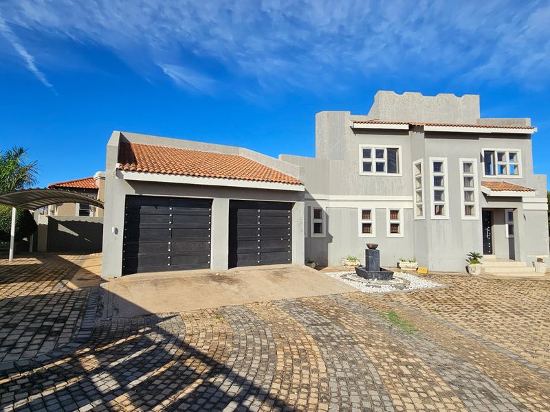 Front elevation of a double-story house featuring a double garage, paved driveway, and a decorative water feature at the entrance.
