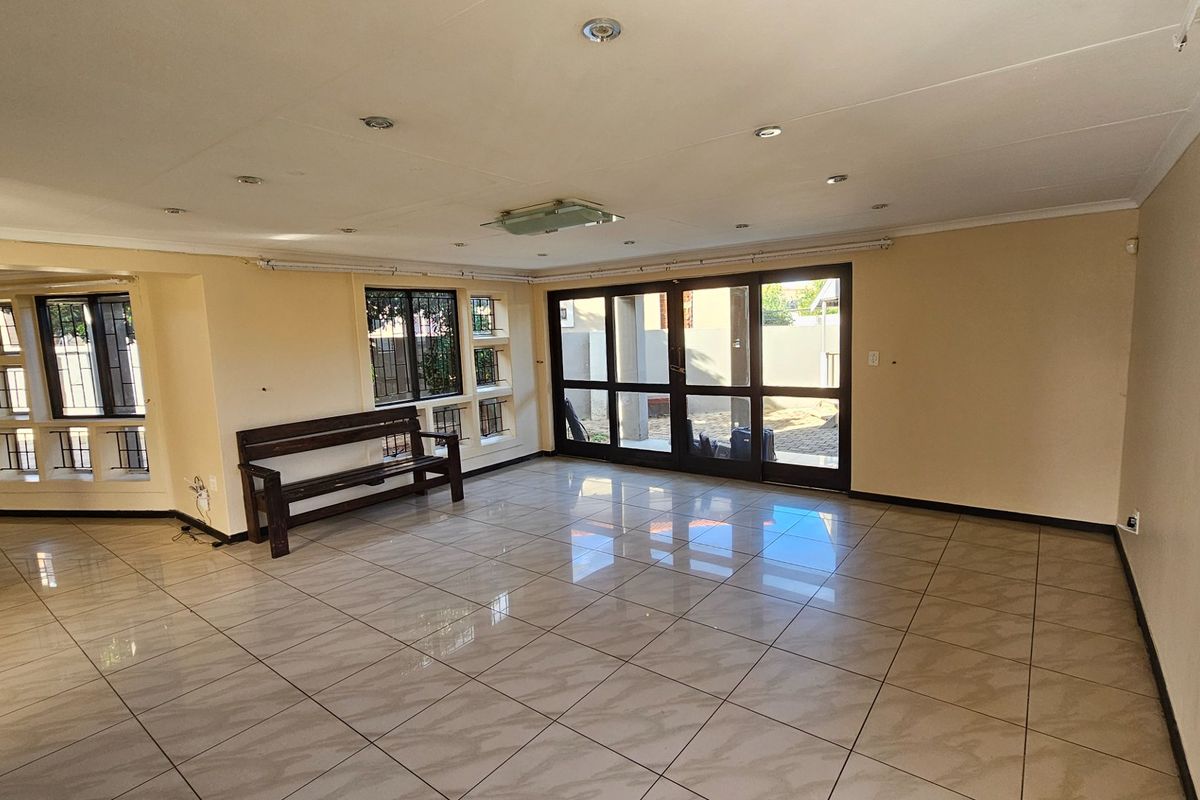 Spacious living area featuring large tiled flooring, recessed ceiling lighting, and expansive glass sliding doors providing direct access to the outdoor patio area.