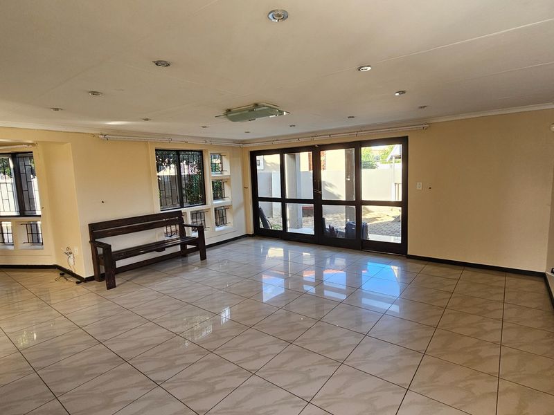Spacious living area featuring large tiled flooring, recessed ceiling lighting, and expansive glass sliding doors providing direct access to the outdoor patio area.