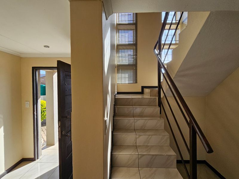 Entrance foyer featuring tiled flooring, a staircase with metal handrails, and a vertical window arrangement providing natural light.