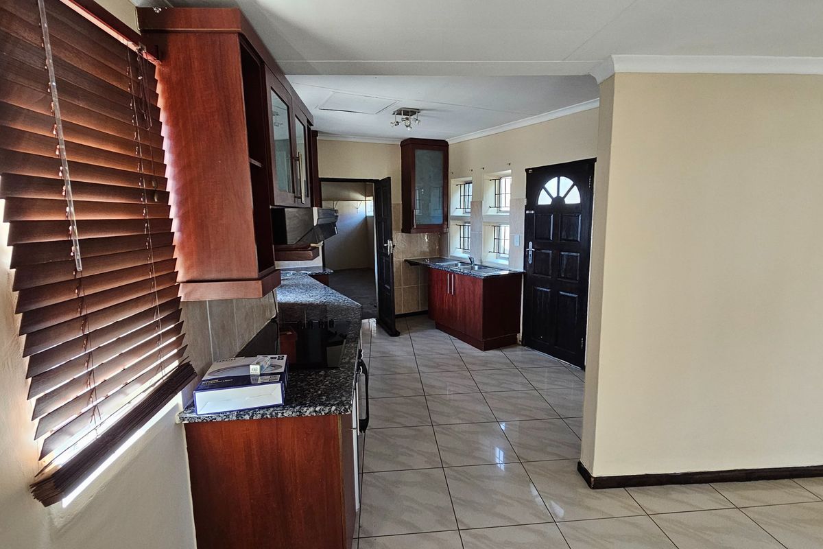 A functional kitchen featuring dark wood cabinetry, granite countertops, tiled flooring, and a direct access door to the exterior.