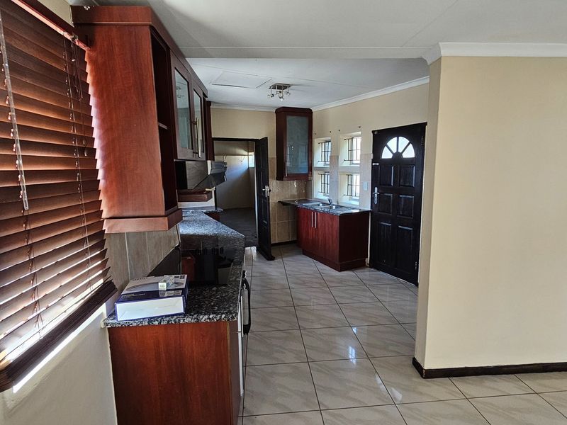 A functional kitchen featuring dark wood cabinetry, granite countertops, tiled flooring, and a direct access door to the exterior.