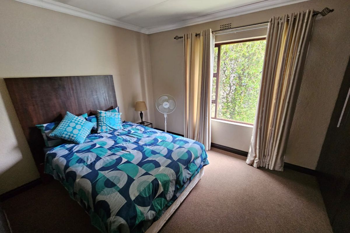 A carpeted bedroom featuring a built-in headboard, crown molding, and a window with curtain rods.