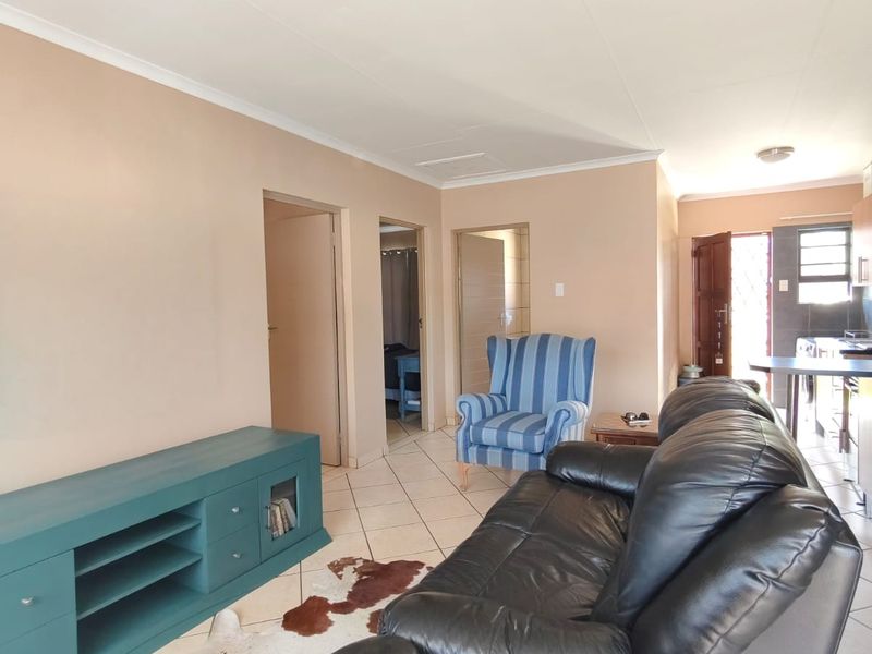 Open plan living area featuring ceramic floor tiles and neutral wall tones, connecting to the kitchen and adjacent rooms.