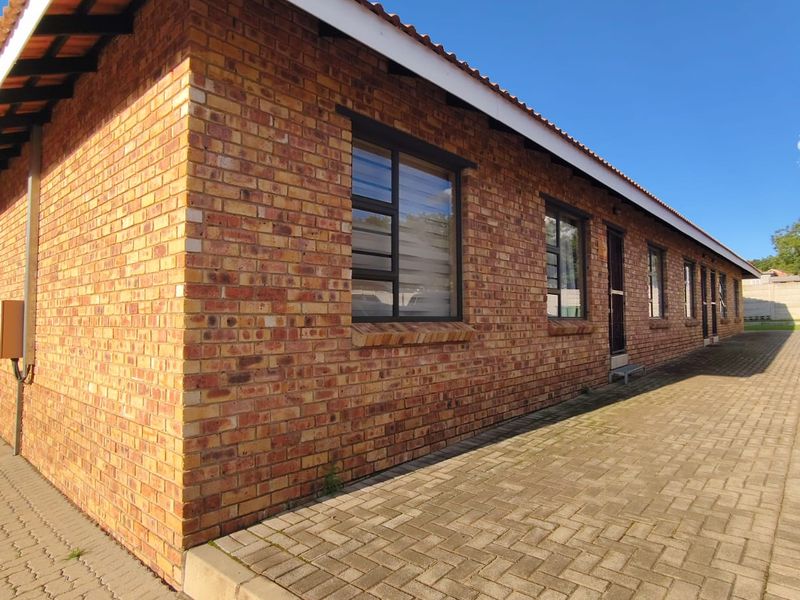 A side view of the townhouse featuring a durable face brick exterior, tiled roof, and paved walkway along the building perimeter.