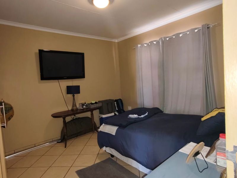 A standard bedroom featuring tiled flooring and neutral wall finishes, providing a functional space with a wall-mounted television mount.