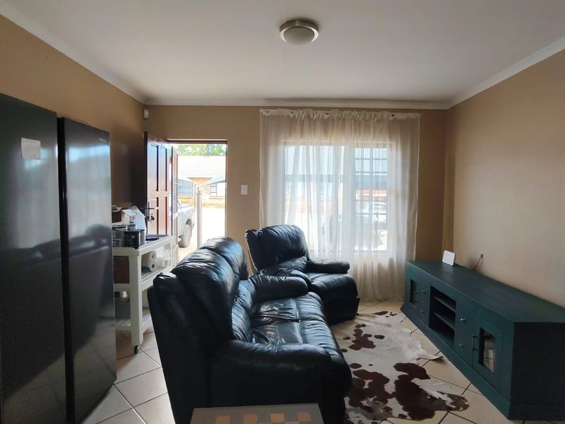 A living room featuring tiled flooring and neutral wall tones, providing a functional space with direct access to the exterior.