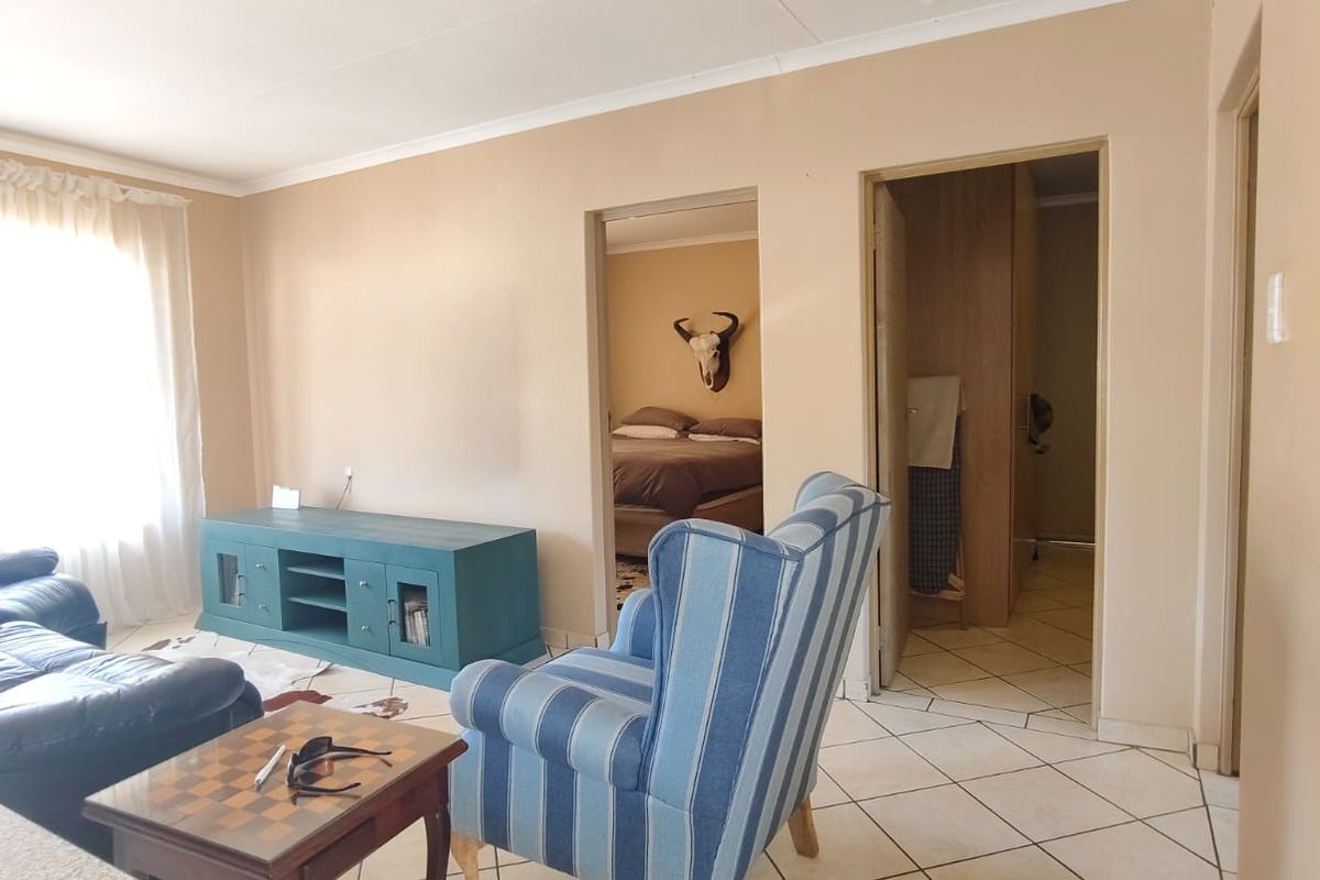 Living area featuring tiled flooring and direct access to adjacent rooms, showing signs of wear on the ceiling finishes.